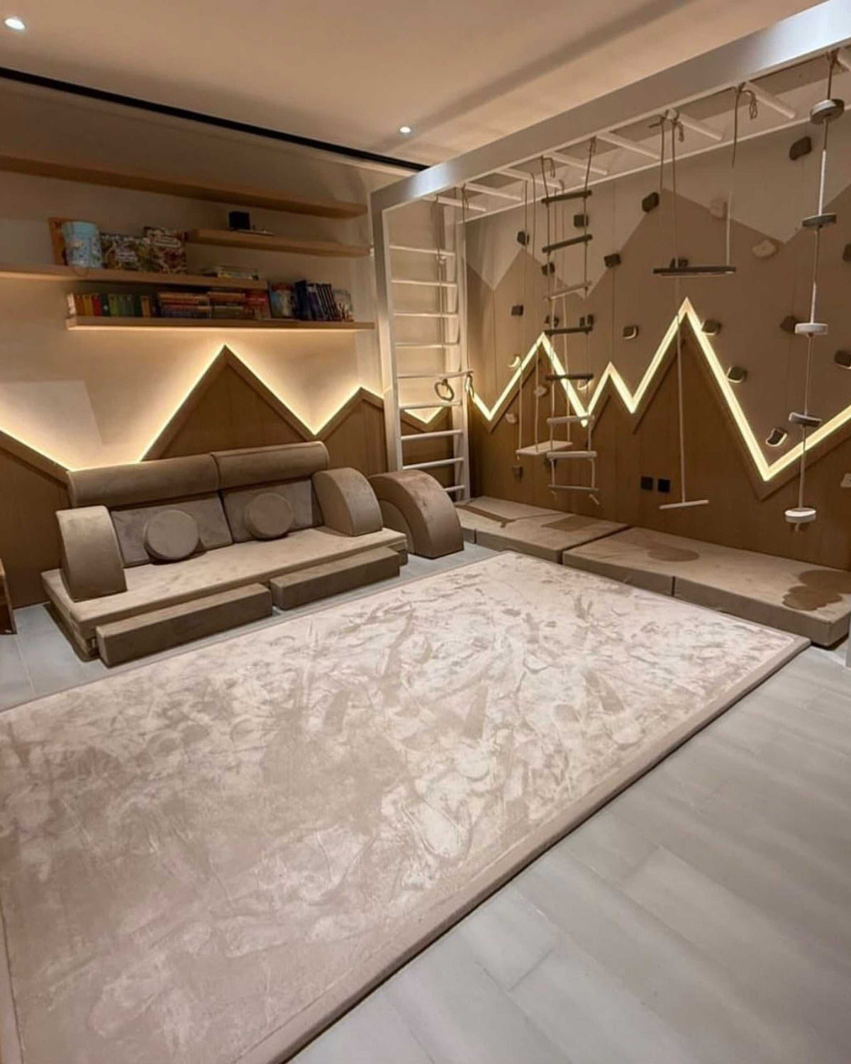 Beige Misk Mat 35mm memory foam mat in a modern kids' playroom with a padded climbing wall, ladder and built-in bookshelf.
