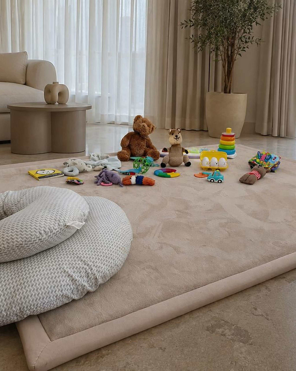 Beige Misk Mat 35mm memory foam mat scattered with baby toys and a nursing pillow in a neutral, modern living room.
