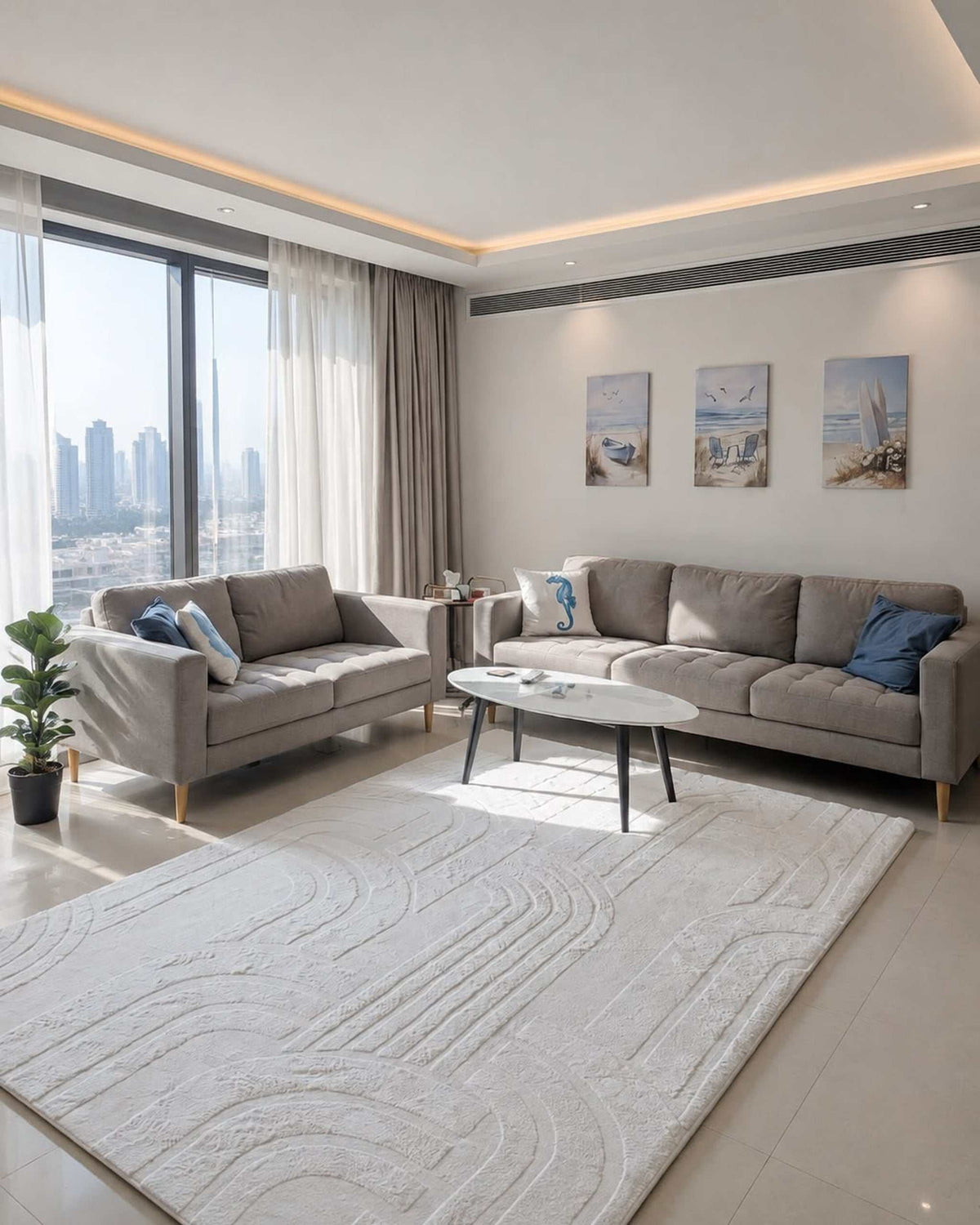Vanilla Cream Misk Mat memory foam mat in front of a grey sofa in a bright living room with a city skyline view and coastal wall art.