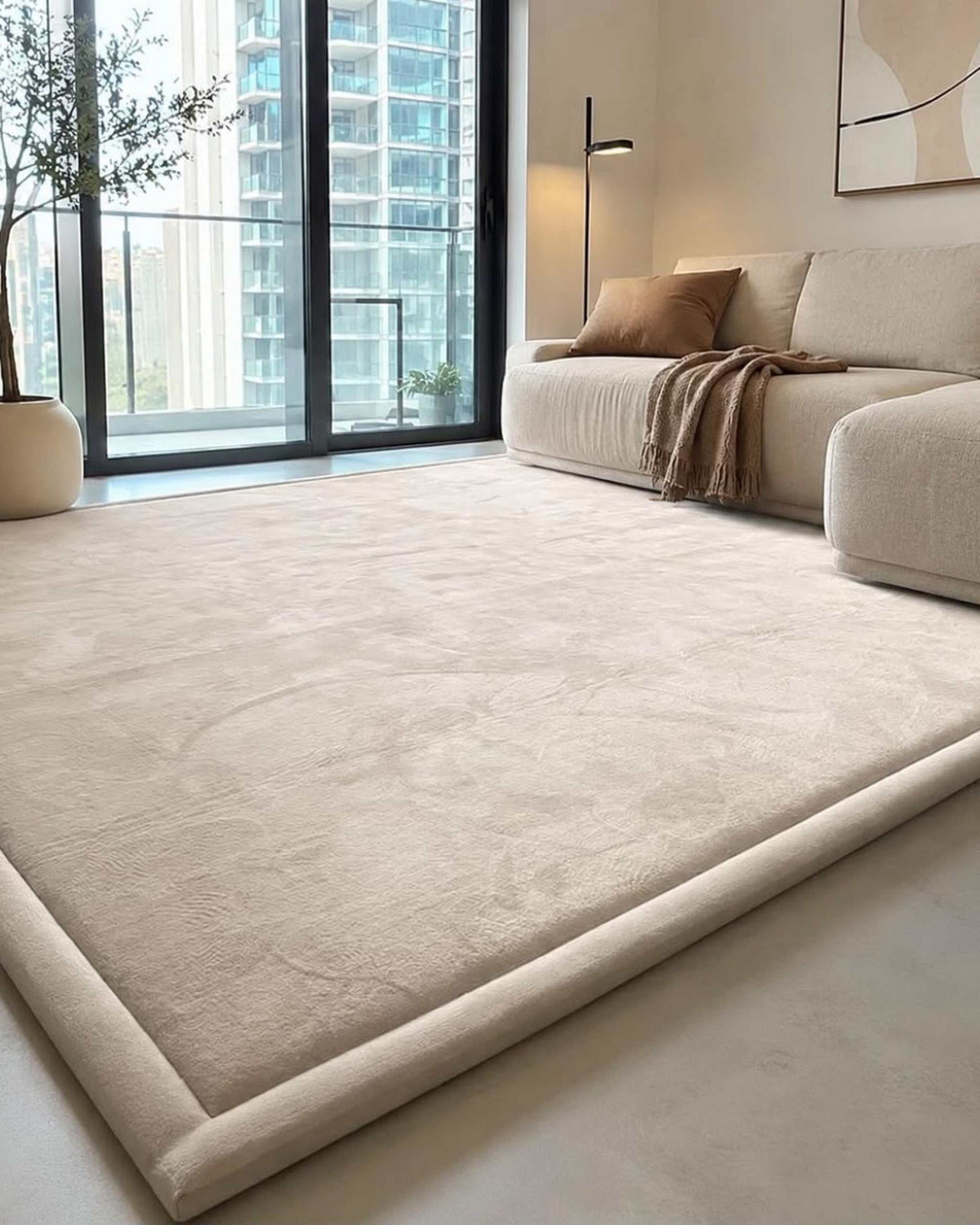 Beige Misk Mat memory foam mat in a bright living room with floor-to-ceiling windows overlooking the city skyline.