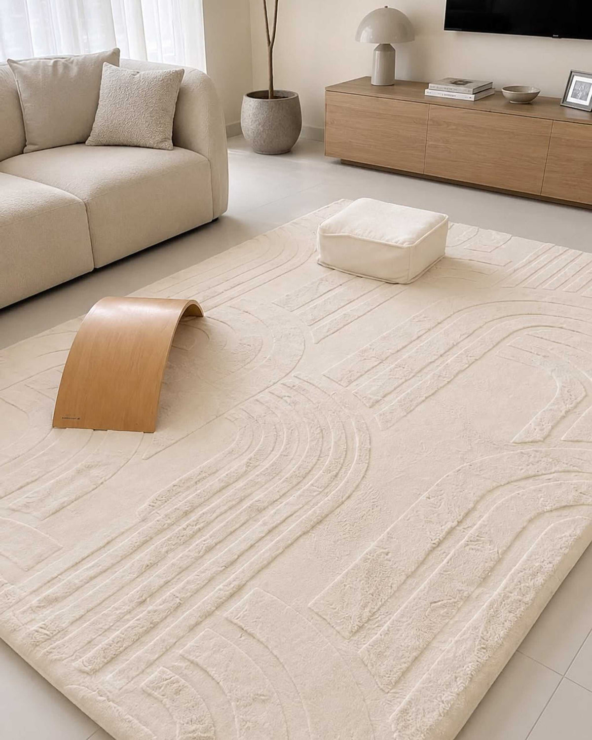 Vanilla Cream Misk Mat memory foam mat in a minimalist living room with a wooden rocking toy, ottoman and TV console.