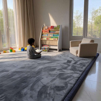 Child sitting and reading a book on a Dark Grey Misk Mat 35mm memory foam mat, next to a bookshelf and armchair.