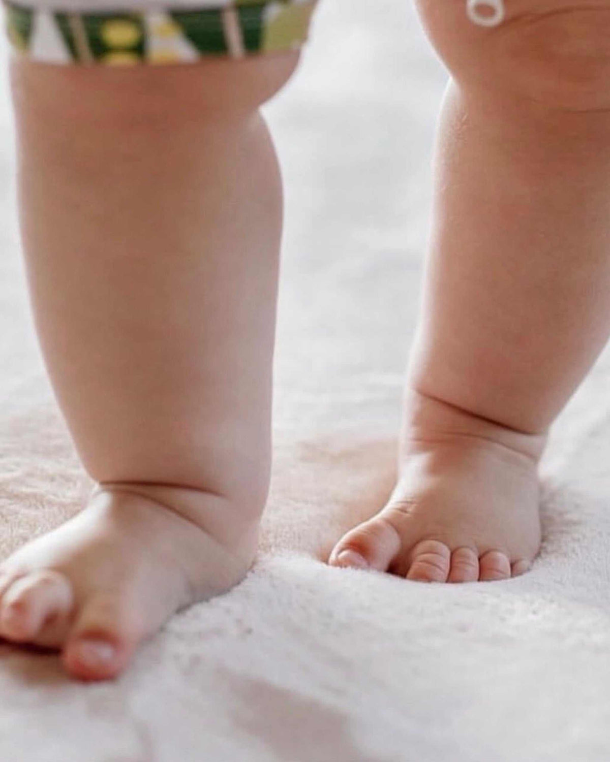 Close-up of a toddler's feet standing on the plush surface of a white Misk Mat 35mm memory foam mat.