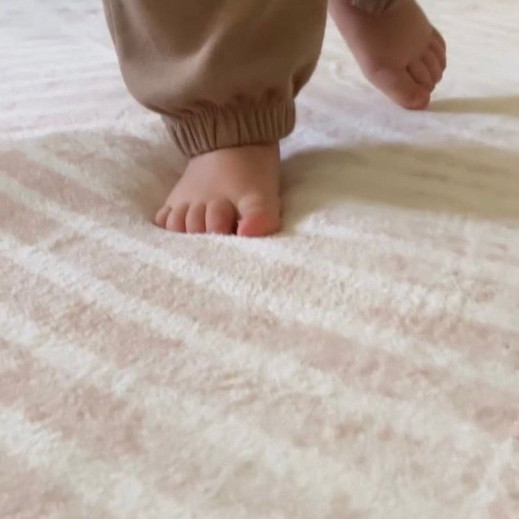 Ivory Arches patterned memory foam mat with a toddlers feet sinking into it showing its cushioning and 35mm thickness