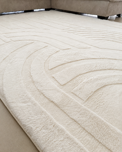 Close-up of the Vanilla Cream Misk Mat's raised 3D arch-pattern texture, with the mat's rounded edge on a wood floor.